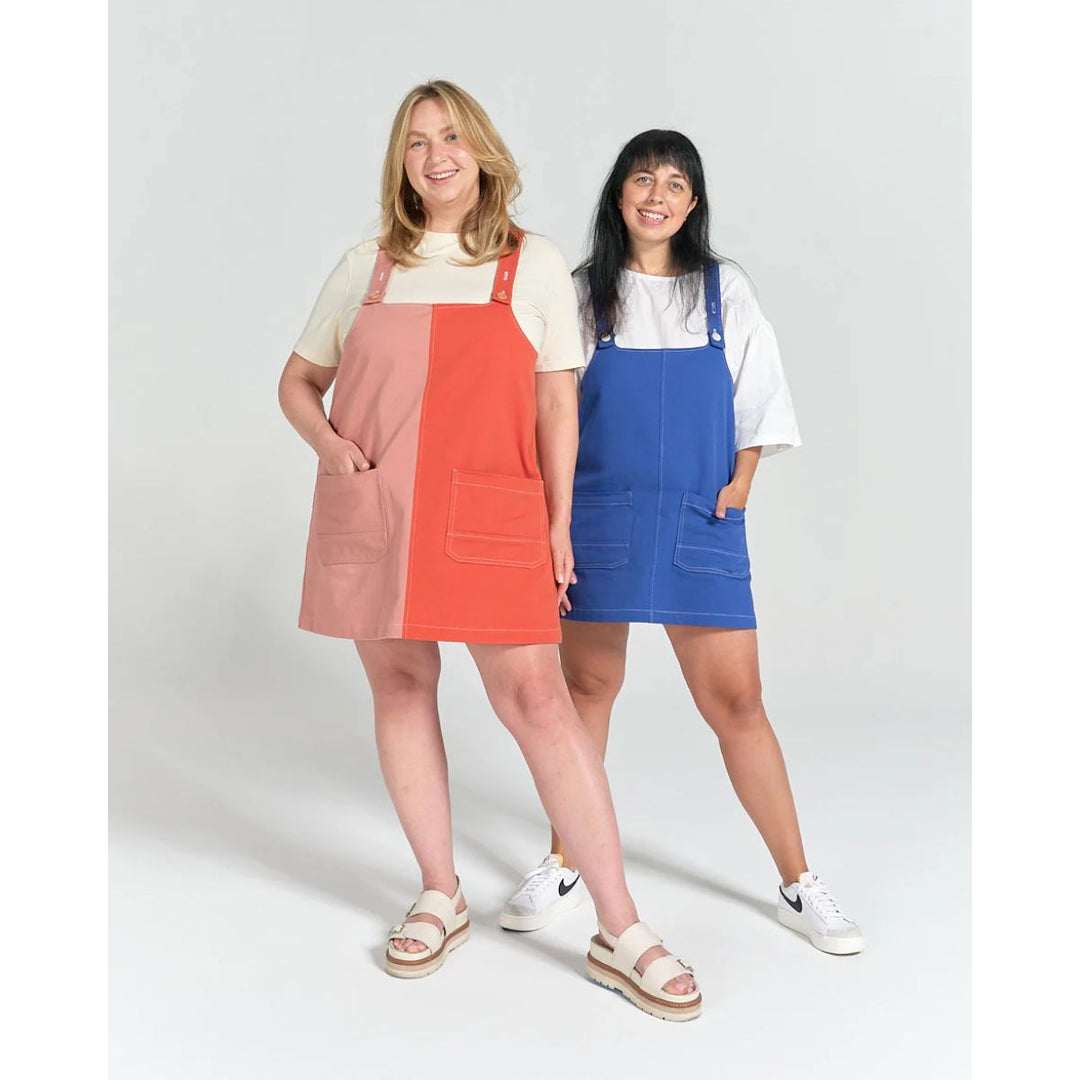 Two women wearing colorful pinafore dresses on a white background