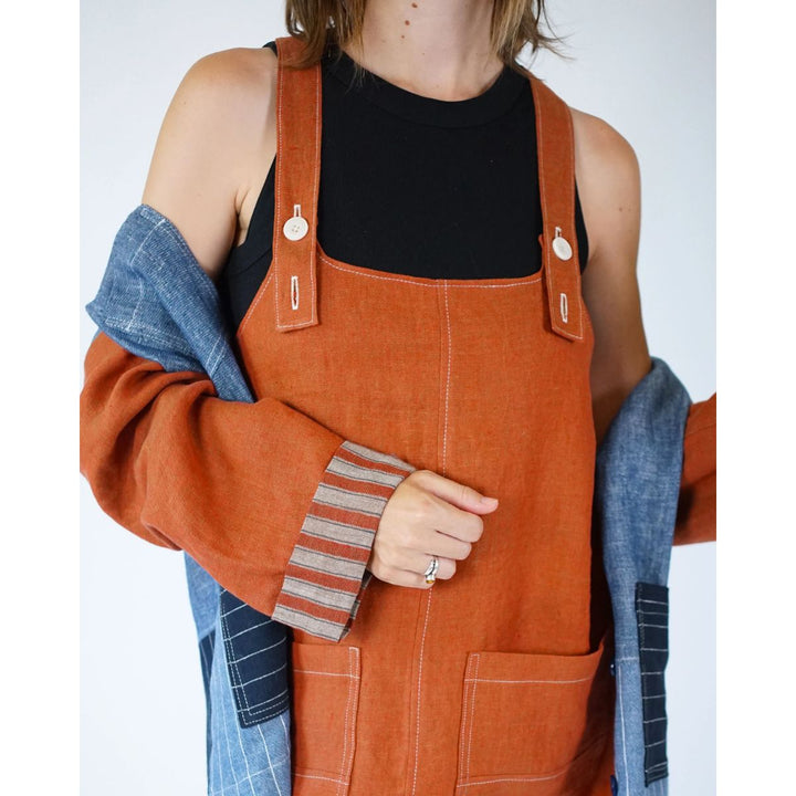 Person wearing an orange denim overalls with a plain background