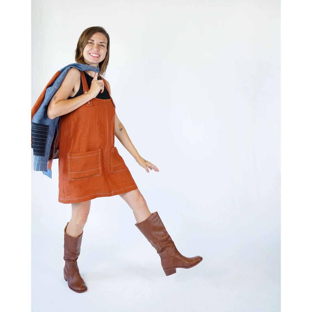 Woman wearing a brown corduroy dress and brown boots on a white background