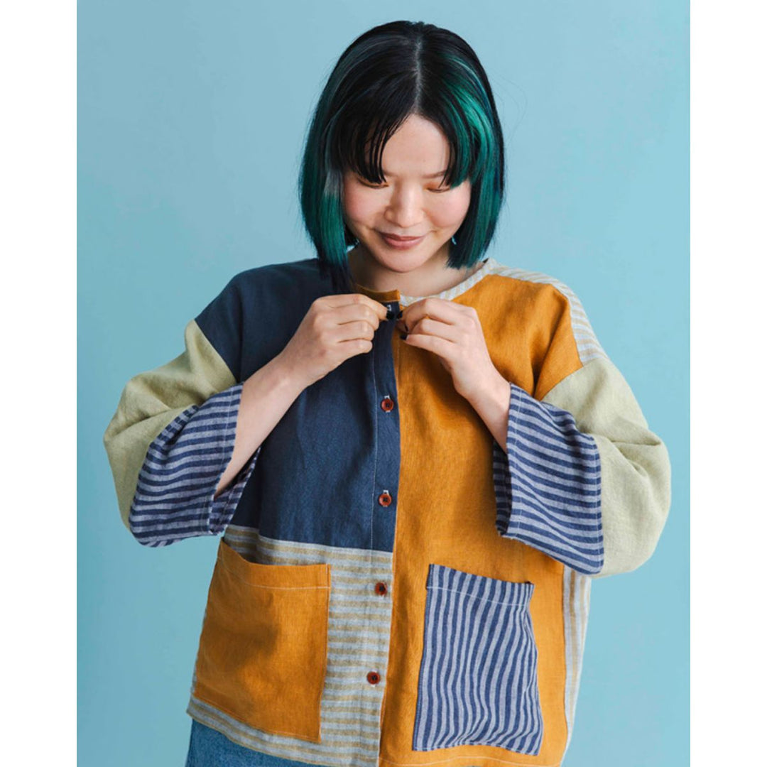 Person wearing a colorful patchwork jacket against a blue background