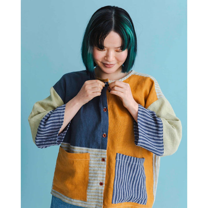 Person wearing a colorful patchwork jacket against a blue background