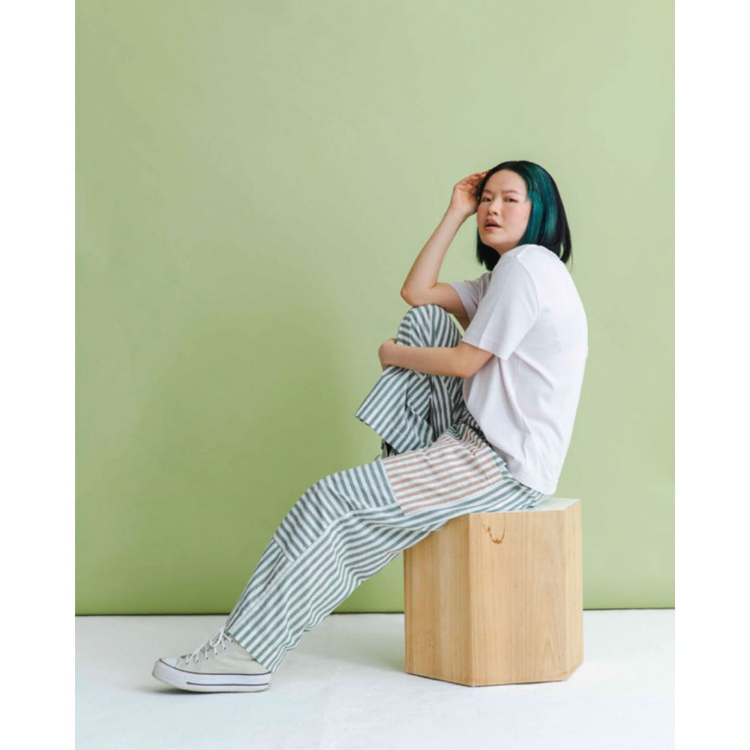 Person sitting on a wooden block against a green wall