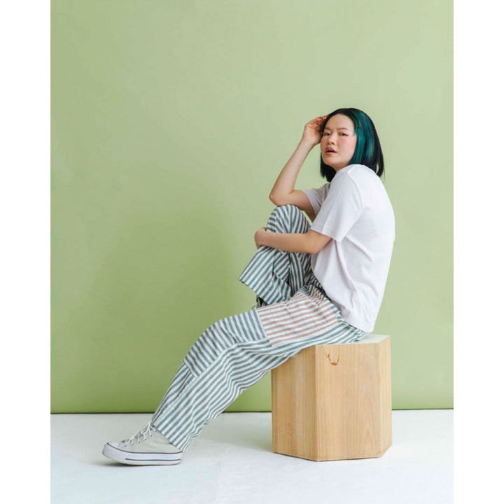 Person sitting on a wooden block against a green wall