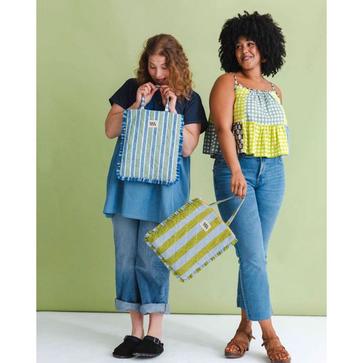 Two women holding colorful striped bags against a green background