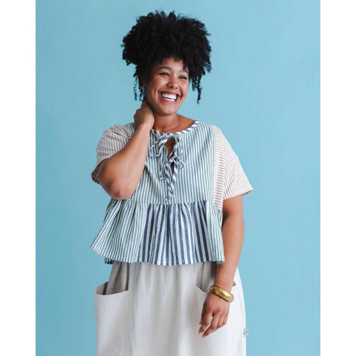 Woman wearing a striped top and beige pants against a blue background