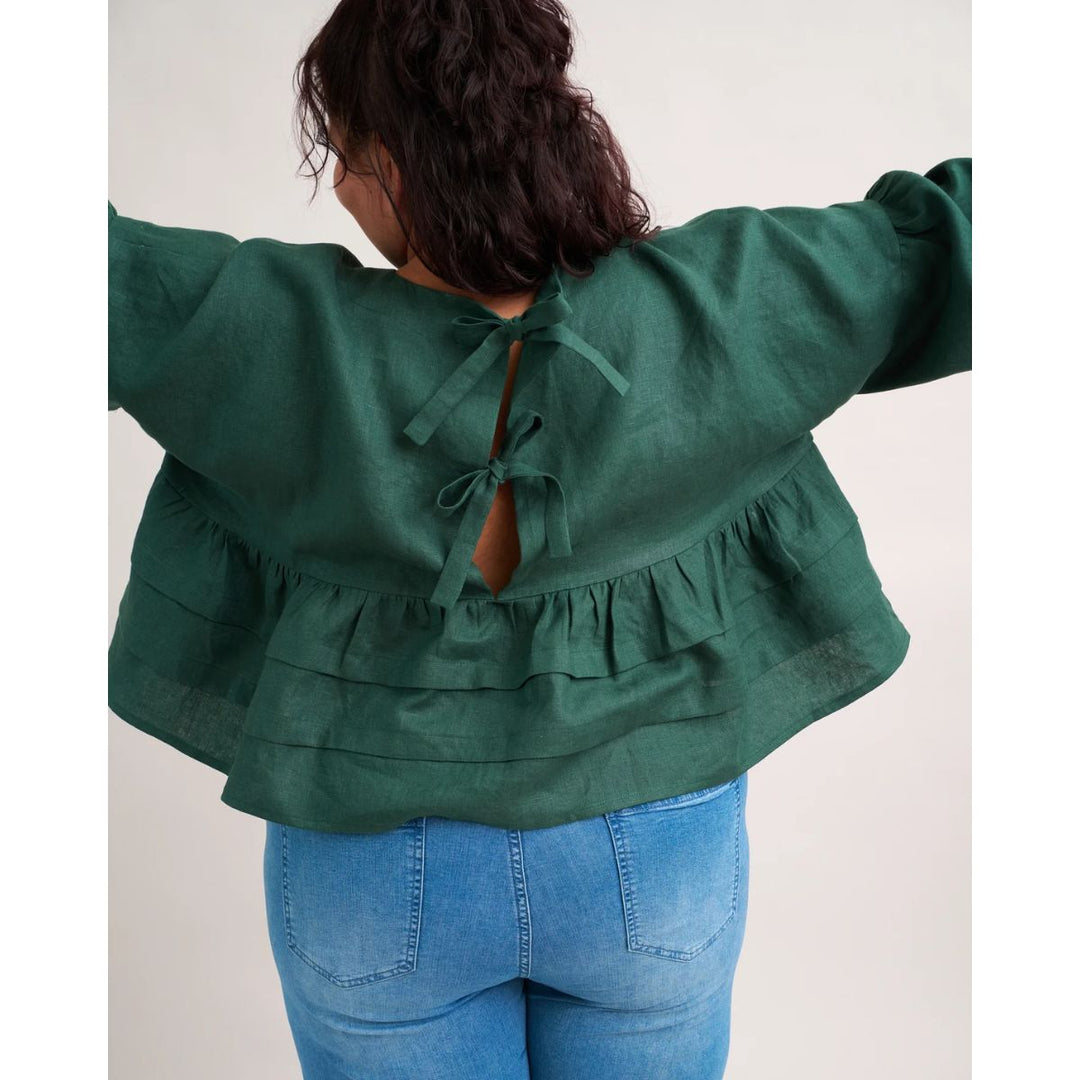Person wearing a green blouse with long sleeves and blue jeans on a white background