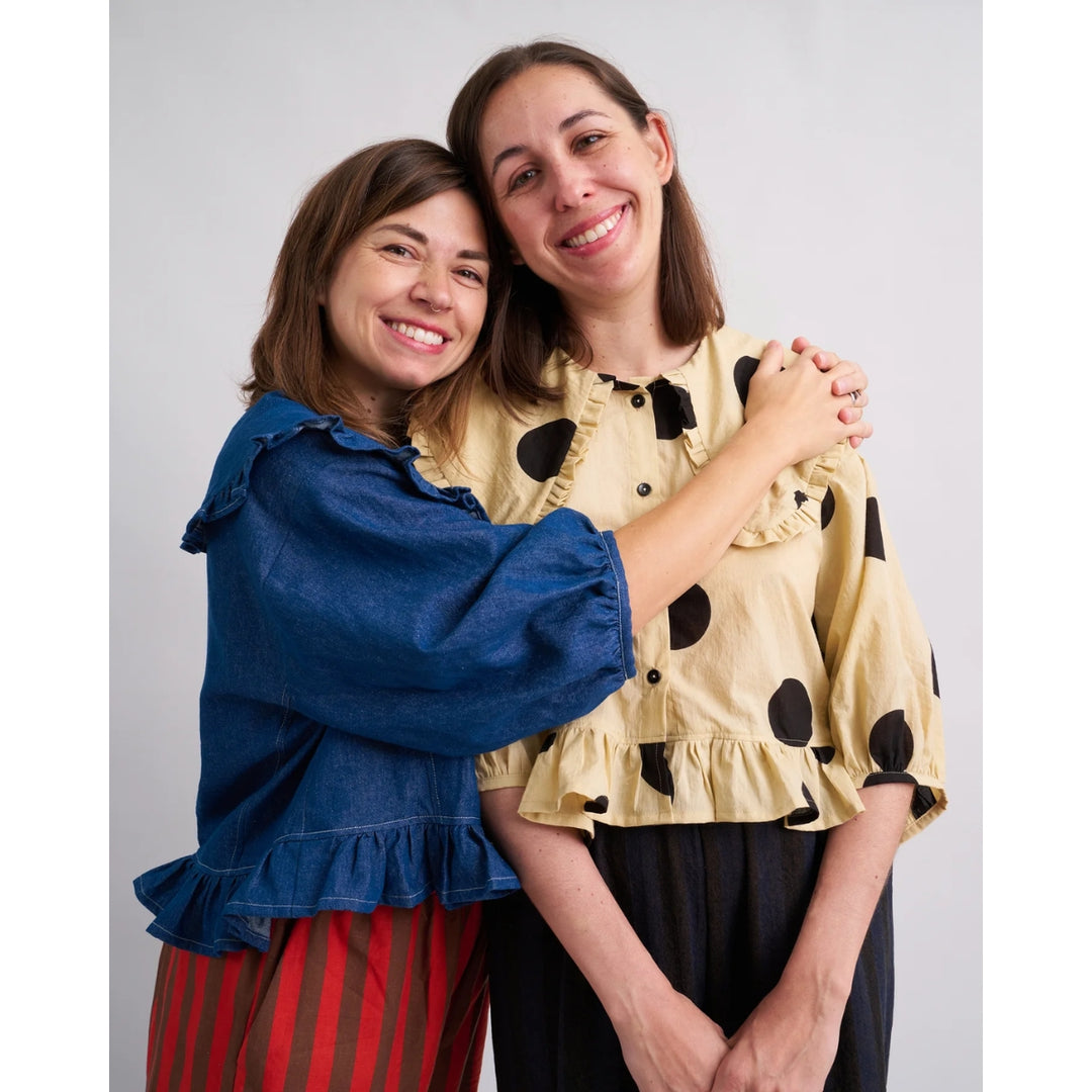 Two women posing together against a plain background