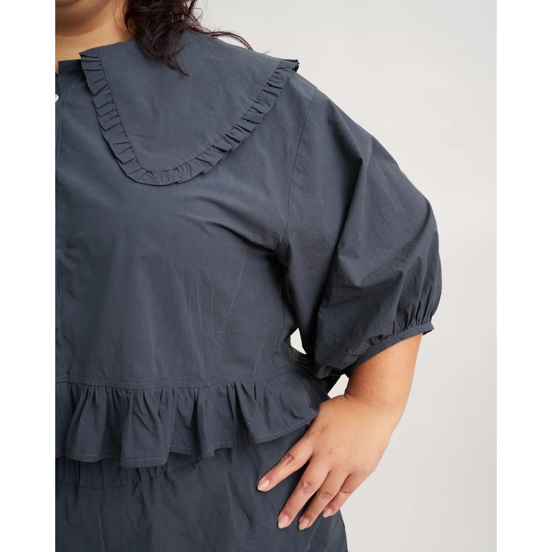 Navy blue dress with ruffled collar and cuffs on a white background