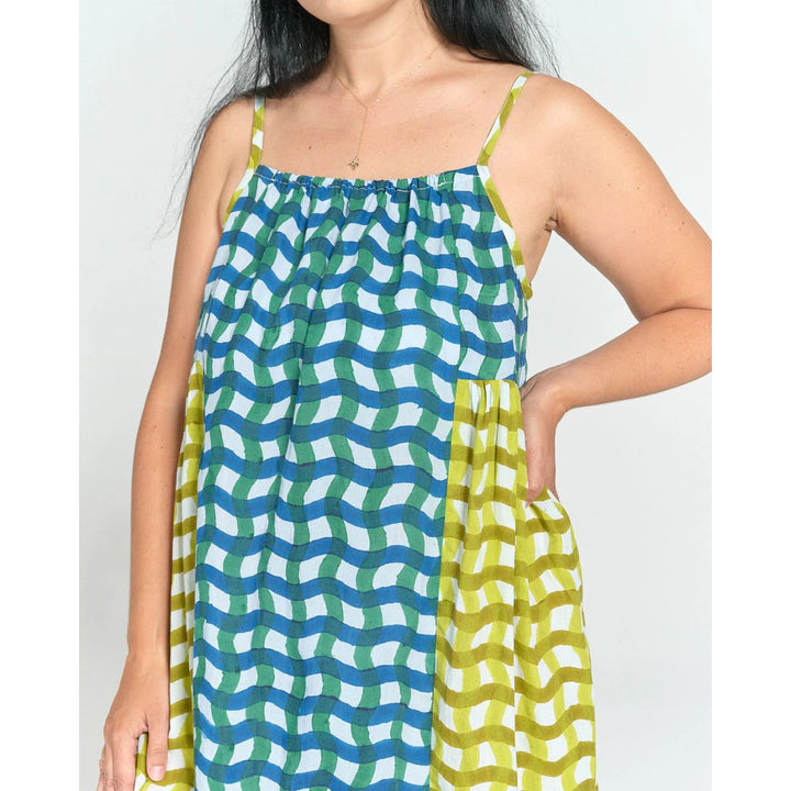 Woman wearing a colorful patterned dress with green and blue design on a white background