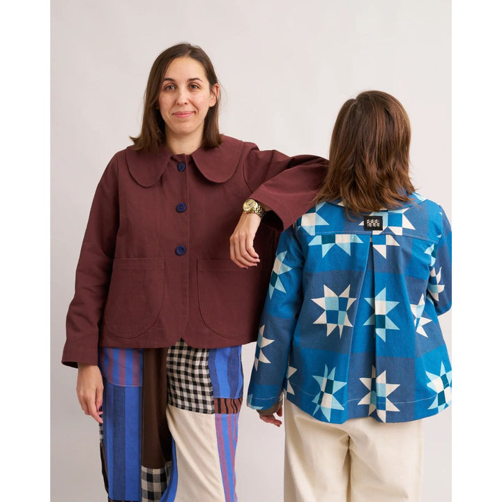Two people wearing colorful jackets, one brown and one with star patterns, on a plain background.