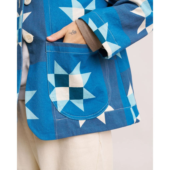 Close-up of a blue quilted jacket with star patterns on a neutral background