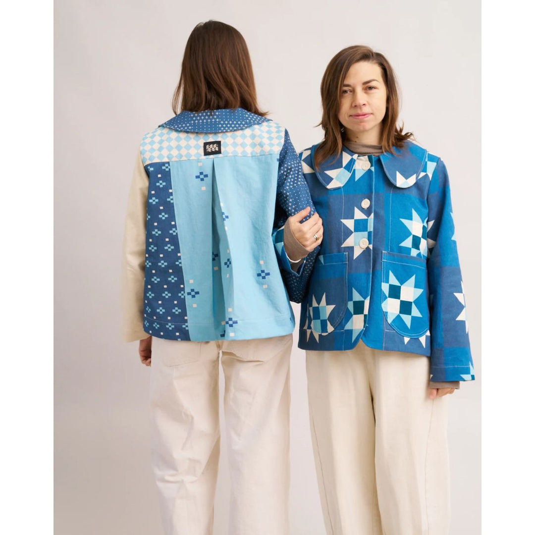 Two people wearing blue patterned jackets on a plain background