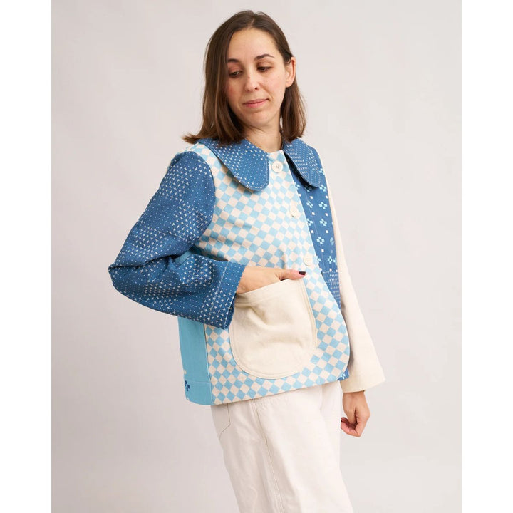 Woman wearing a blue and white checkered jacket with a white background