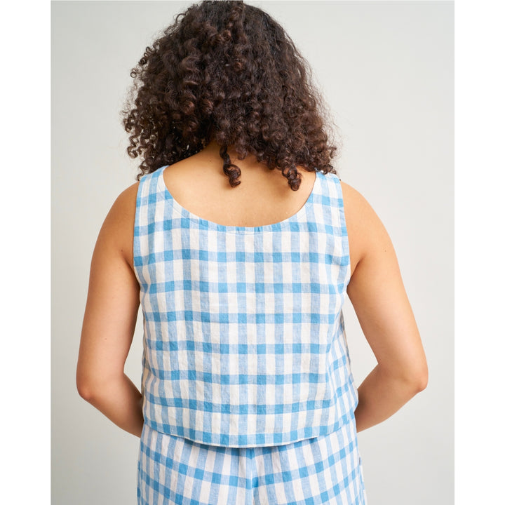 A person shown from the back wearing a sleeveless white top with a light blue gingham check pattern, paired with matching bottoms, against a plain light gray studio background.