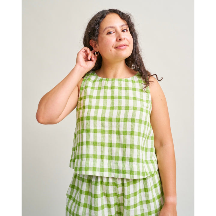 A woman modeling a sleeveless green and white gingham check top and matching bottoms against a plain light gray studio background.