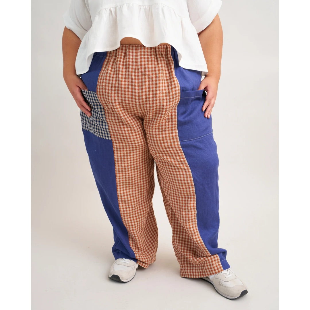 Person wearing a unique pants design with checkered and blue sections on a white background