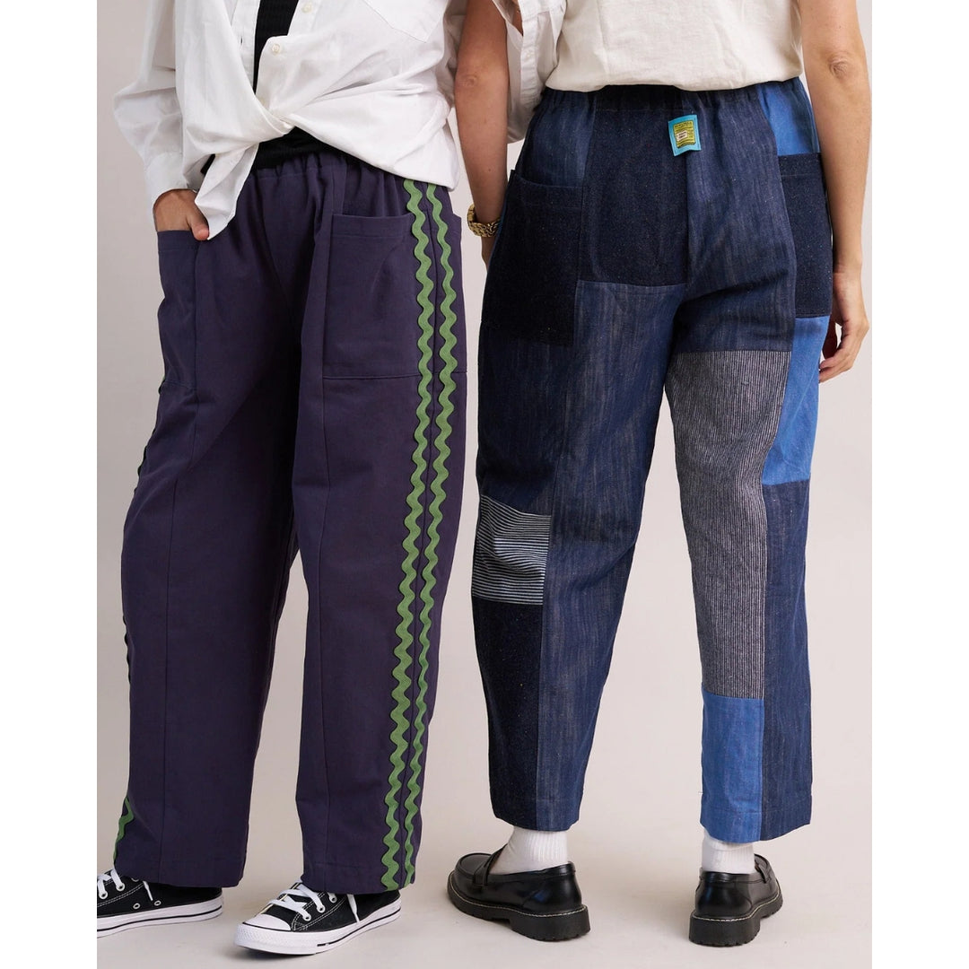 Two people wearing patchwork jeans with different patterns on a plain background
