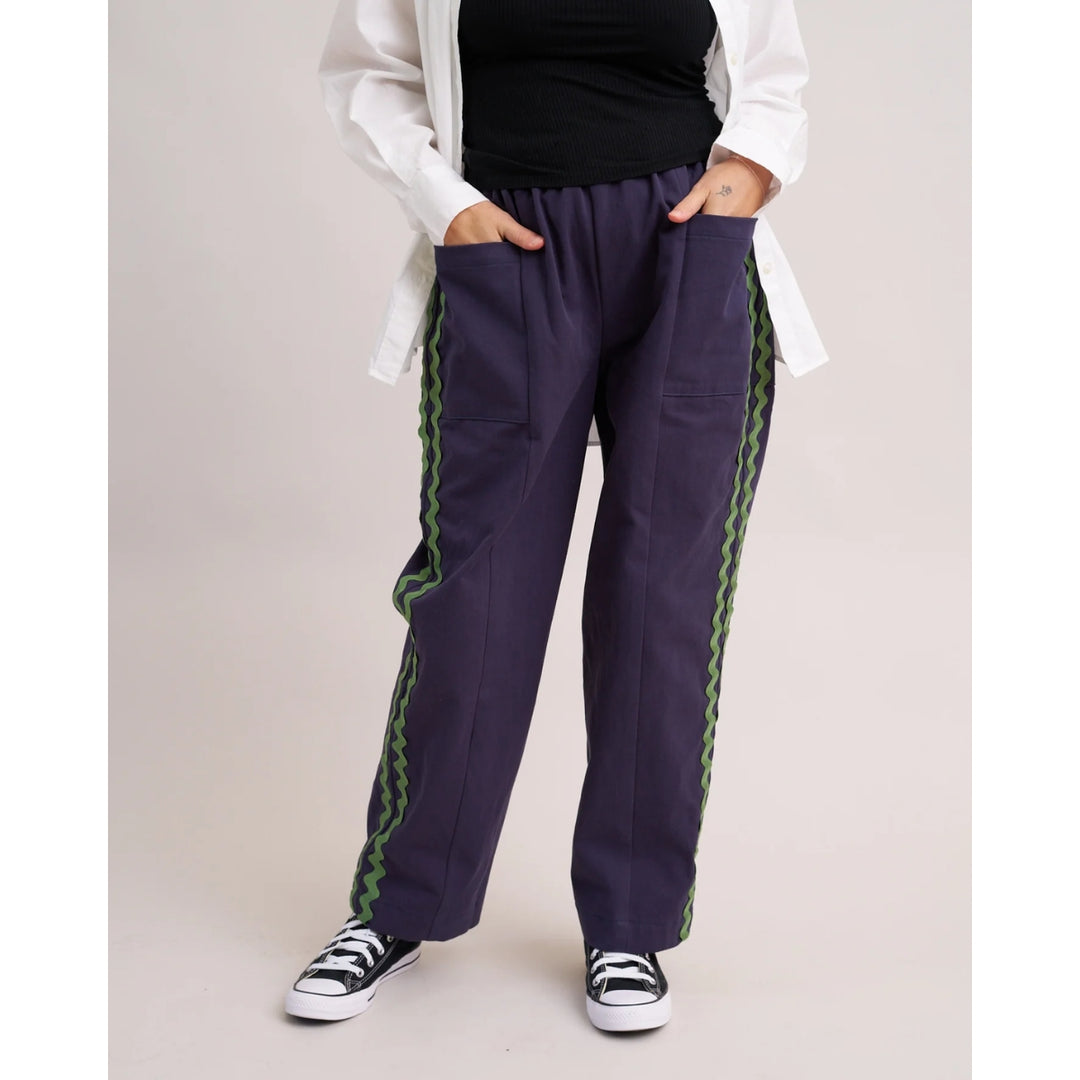 Person wearing navy pants with green trim on a plain background