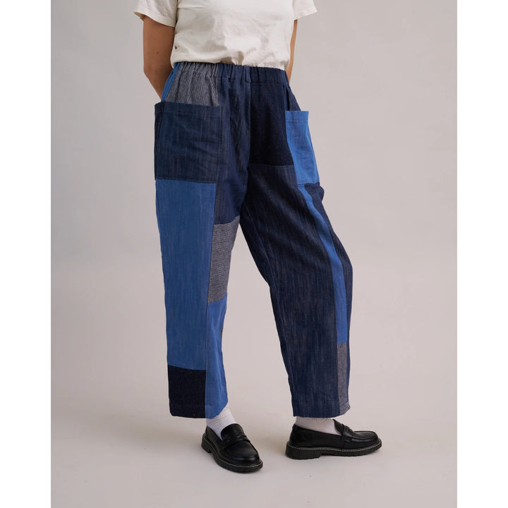 Person wearing blue patchwork pants on a plain background