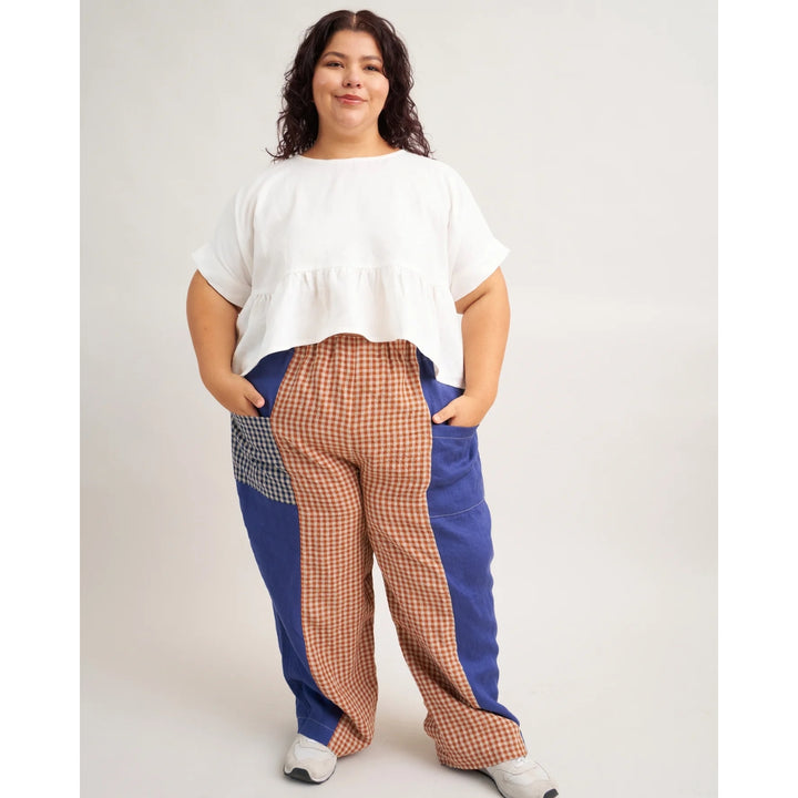 Person wearing a white top and plaid pants with blue accents on a plain background