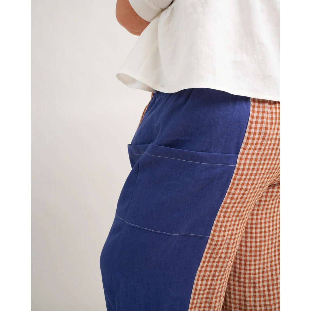 Person wearing a blue and checkered apron on a plain background