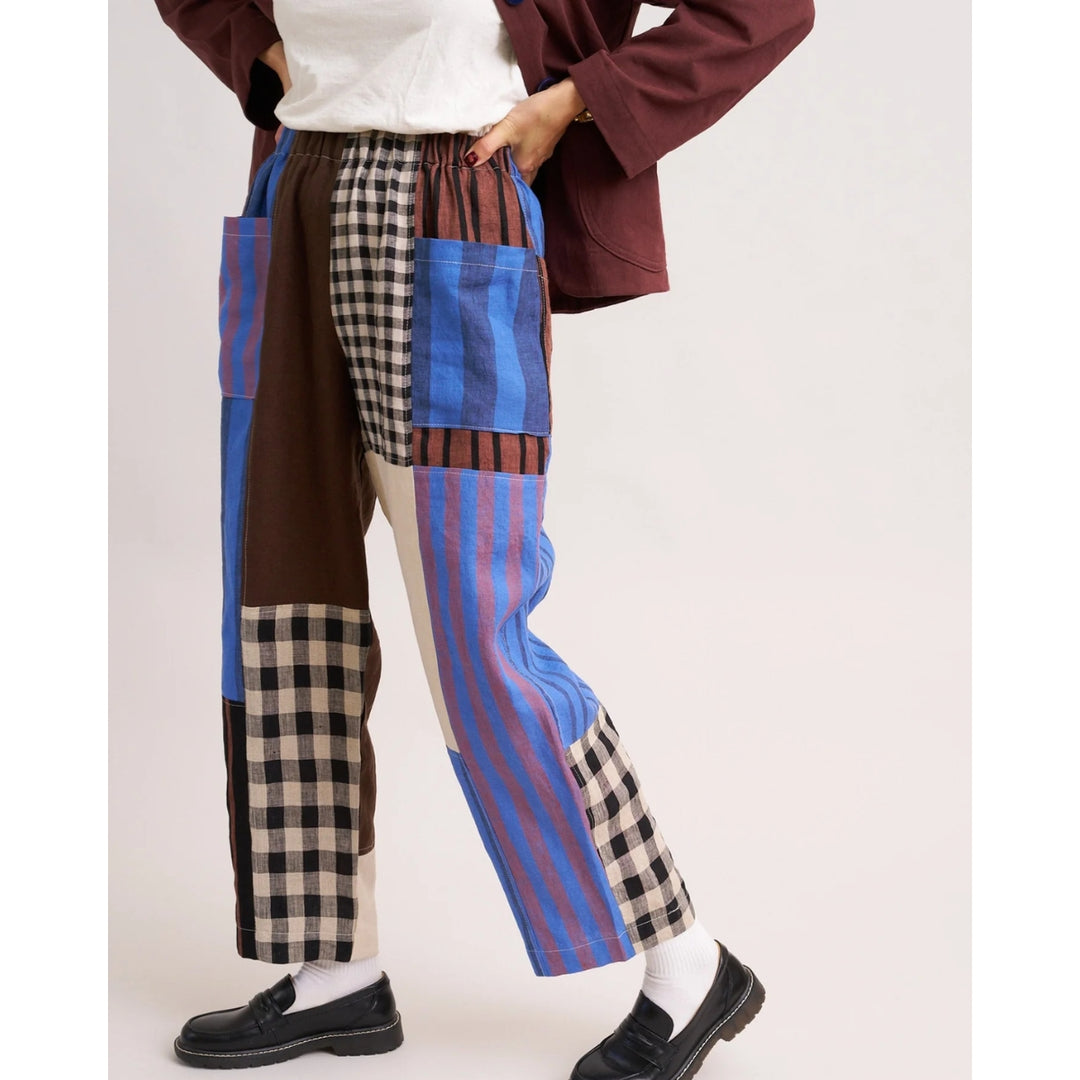 Person wearing patchwork pants with plaid and striped patterns on a white background