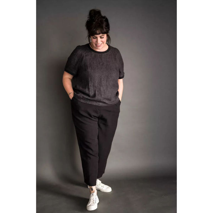 Person wearing a black outfit with white sneakers against a gray background