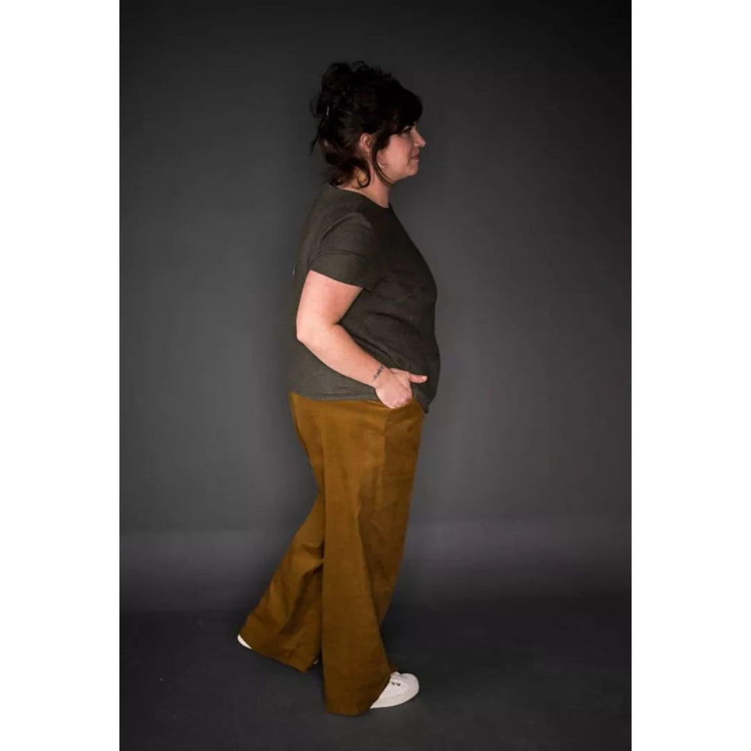 Person wearing a green shirt and brown pants against a dark background