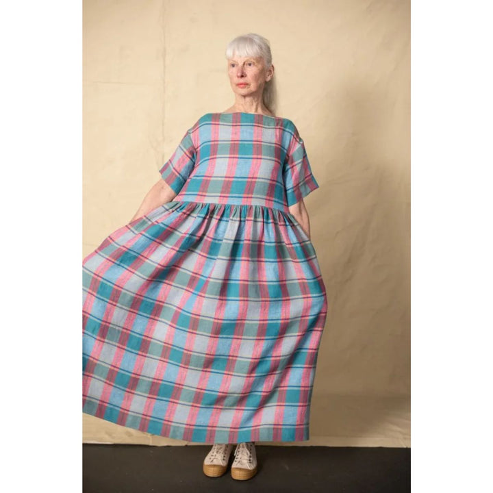 Woman wearing a plaid dress against a beige background