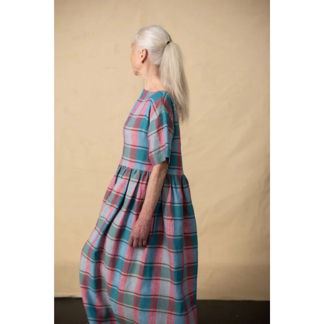 Woman wearing a plaid dress against a beige background