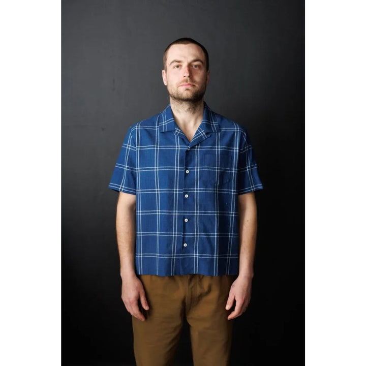 Man wearing a blue plaid shirt against a black background