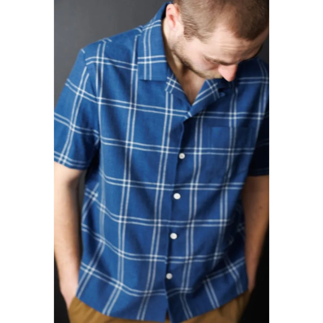 Man wearing a blue plaid shirt against a plain background
