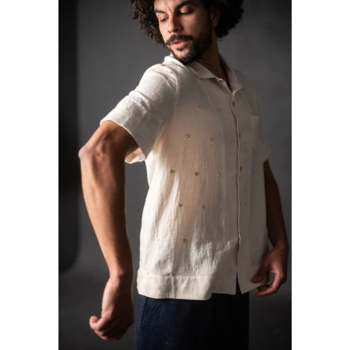 Man wearing a white short-sleeve shirt against a dark background