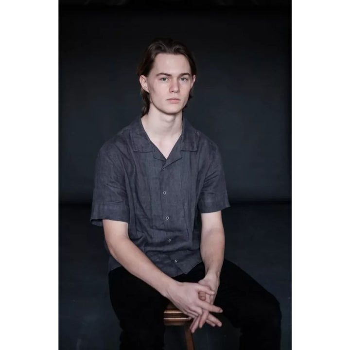 Person wearing a dark shirt sitting against a black background