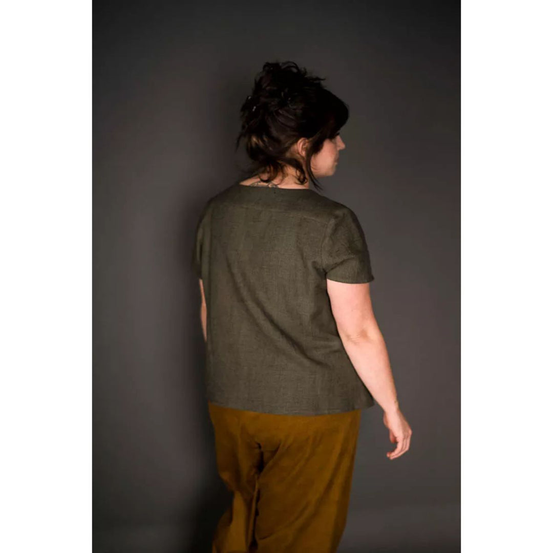 Person wearing a green shirt and brown pants against a gray background