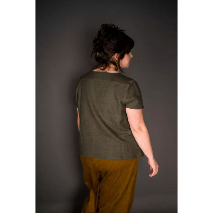 Person wearing a green shirt and brown pants against a gray background