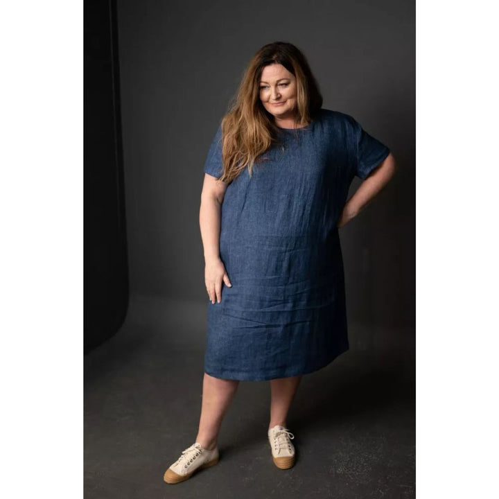 Woman wearing a blue dress standing against a dark background