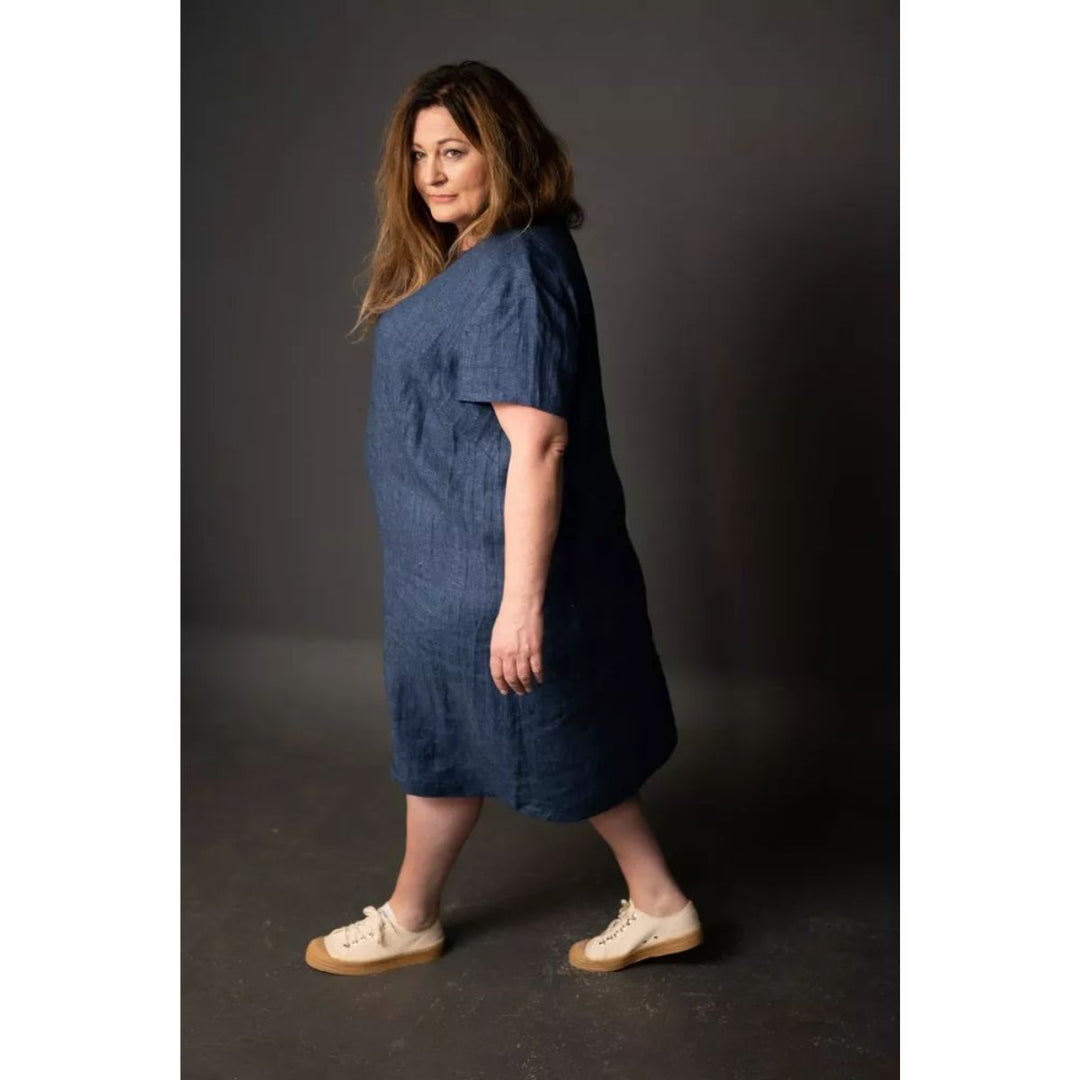 Woman wearing a blue dress standing against a dark background