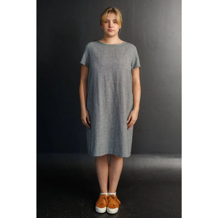 Woman wearing a gray dress against a dark background