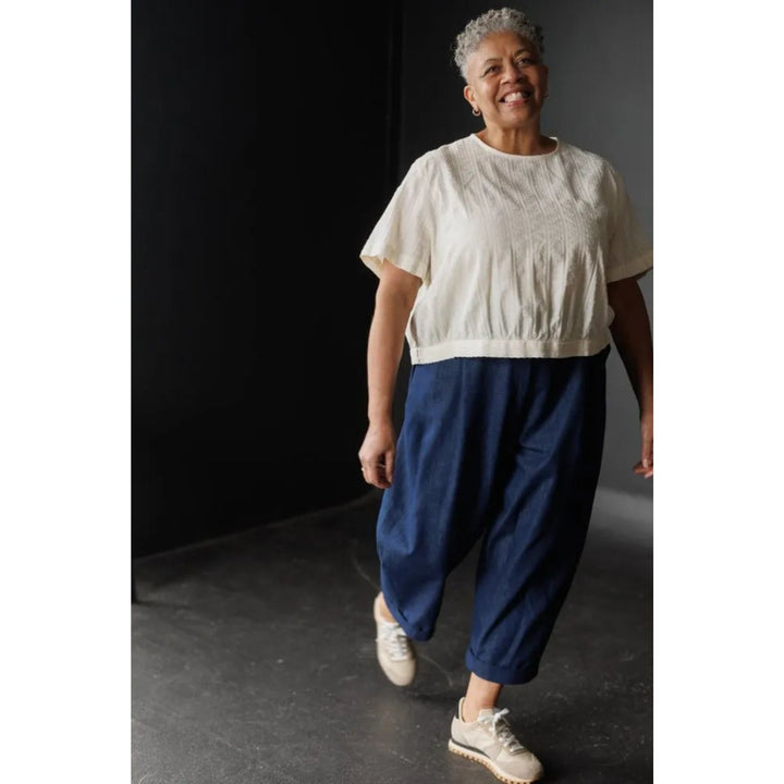 Person wearing a white top and blue pants against a dark background