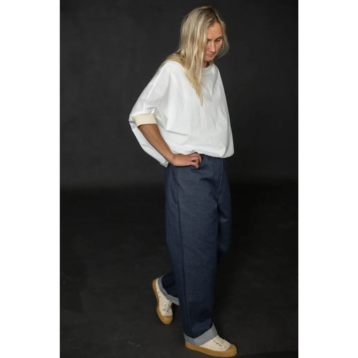 Person wearing a white shirt and blue pants against a black background