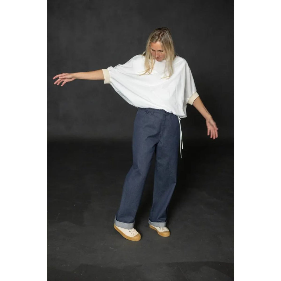 Person wearing a white top and blue pants on a dark background