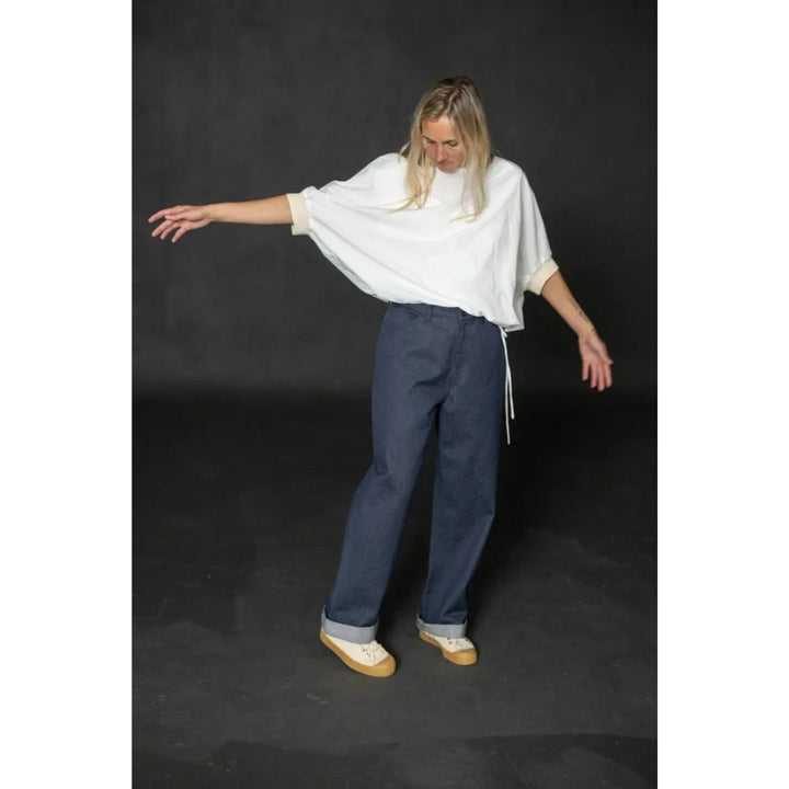 Person wearing a white top and blue pants on a dark background