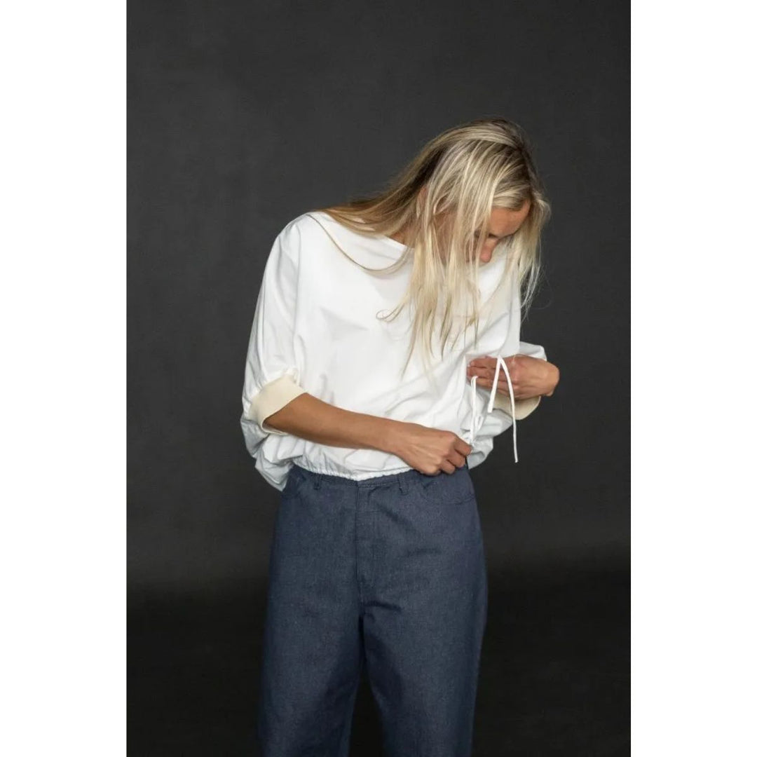 Person wearing a white shirt and blue pants against a dark background
