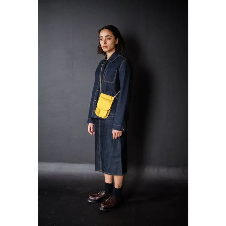 Person wearing a denim outfit with a yellow pocket against a dark background