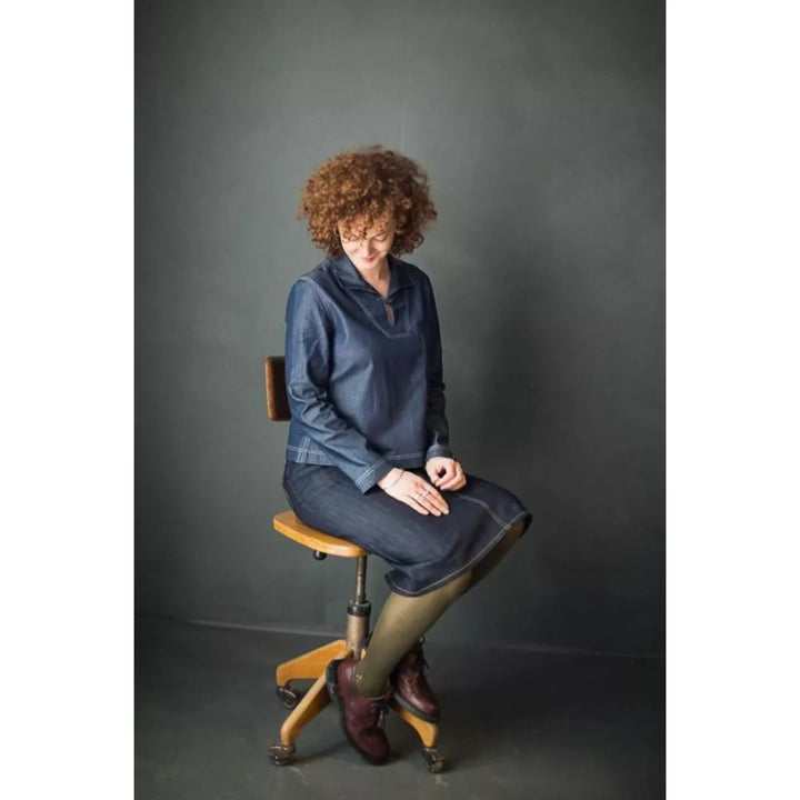 Woman sitting on a stool against a dark gray background
