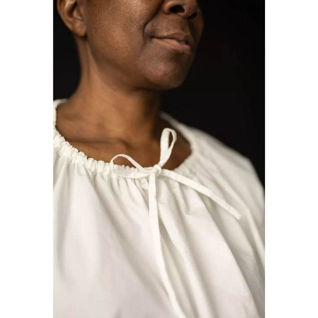 Person wearing a white blouse with a black background