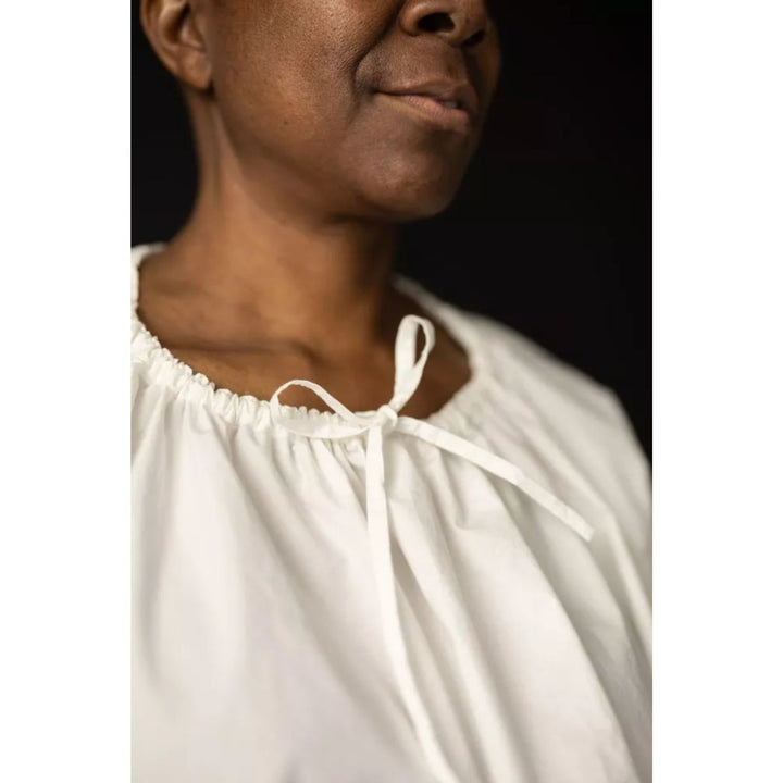 Person wearing a white blouse with a black background