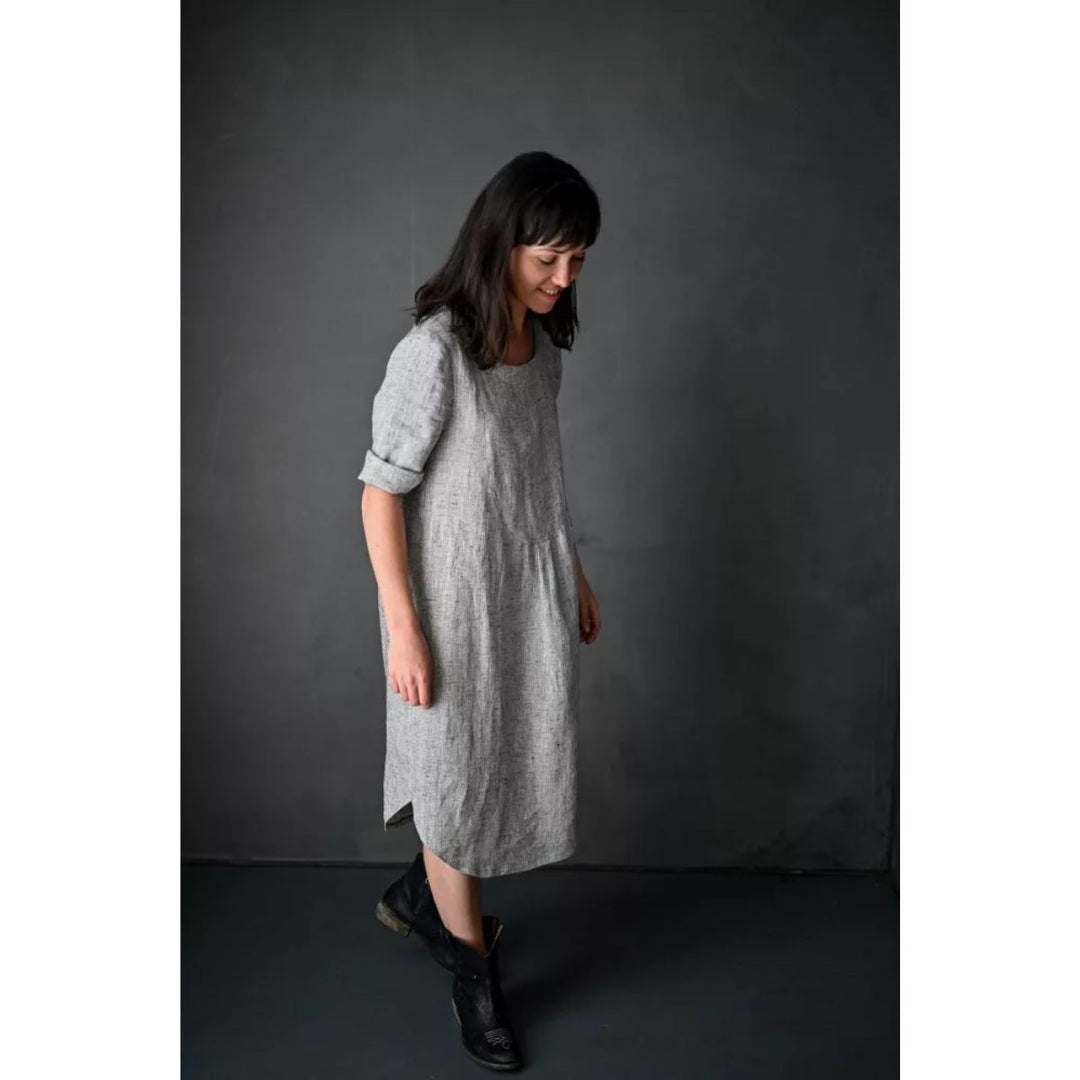 Woman wearing a gray dress against a dark background