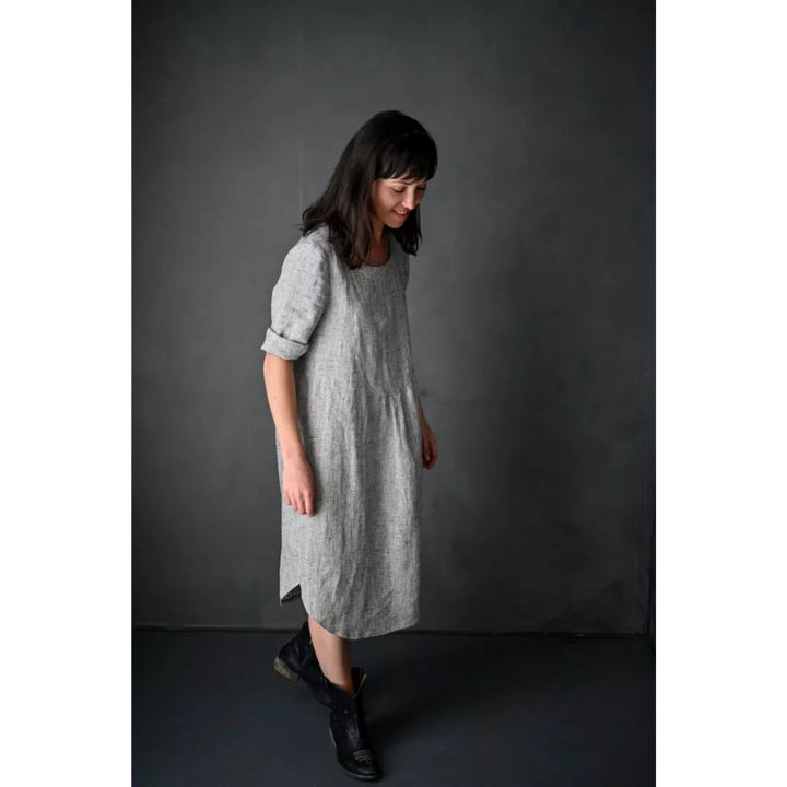 Woman wearing a gray dress against a dark background